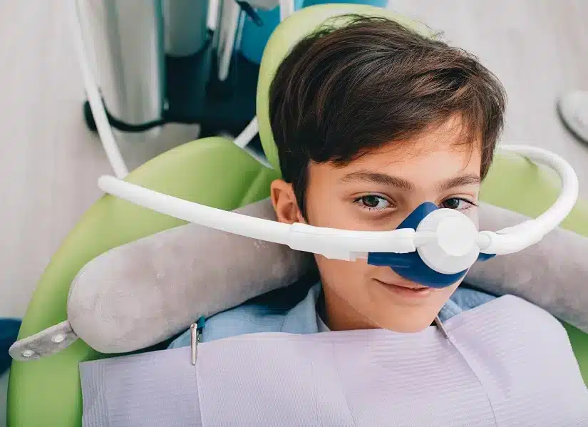 Young boy sitting in a dental chair with a nitrous oxide mask on, preparing for a safe dental procedure
