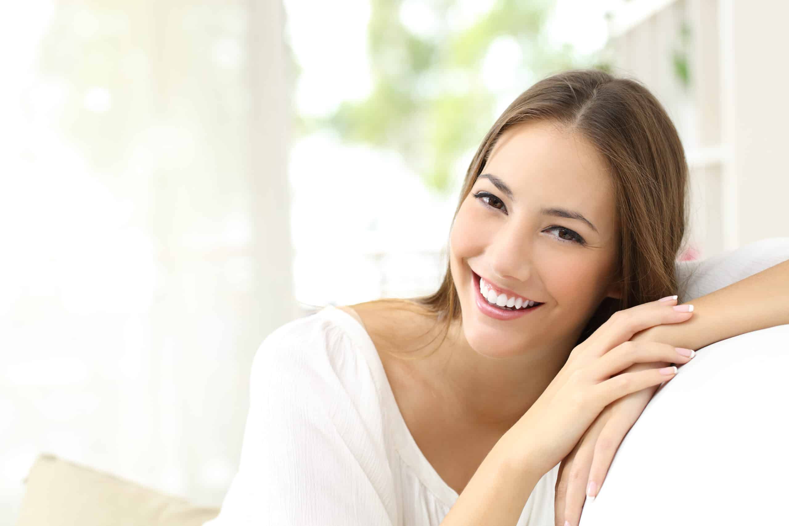 Young woman with healthy gums and a bright smile, resting indoors and looking relaxed