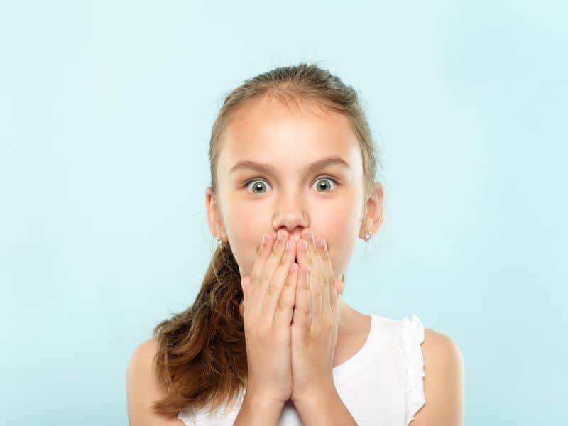 Shocked young girl covering her mouth after knocking out a tooth