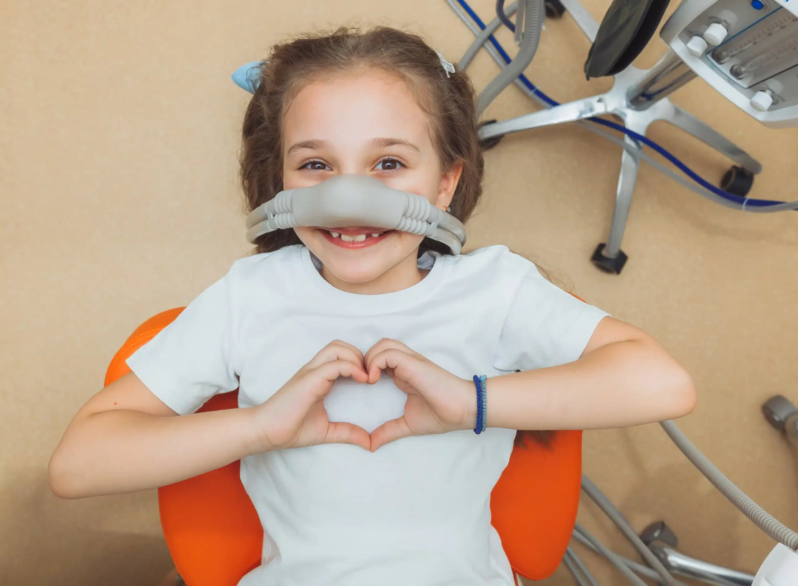 Smiling child lying in a dental chair wearing a nitrous oxide mask during a dental appointment