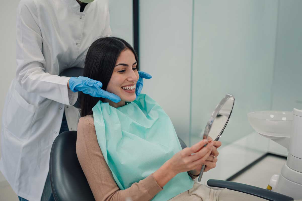 Smiling patient looking in mirror after dental examination or treatment showing improved smile