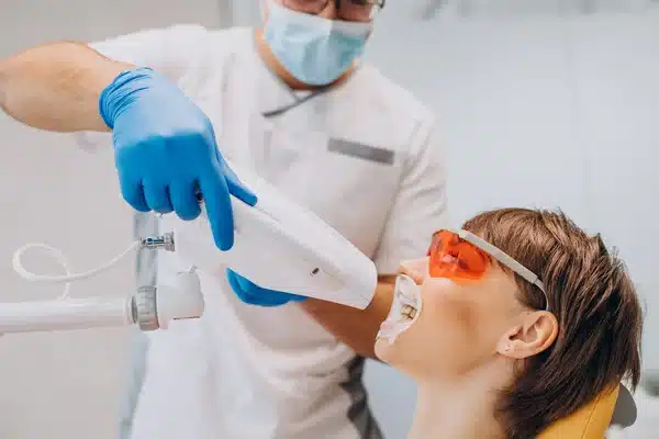 Dentist using a dental laser on a patient wearing protective glasses during a laser dentistry procedure.